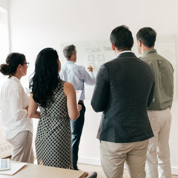 a group of business people looking at a white board with text on it a group of business people looking at a white board with text on it