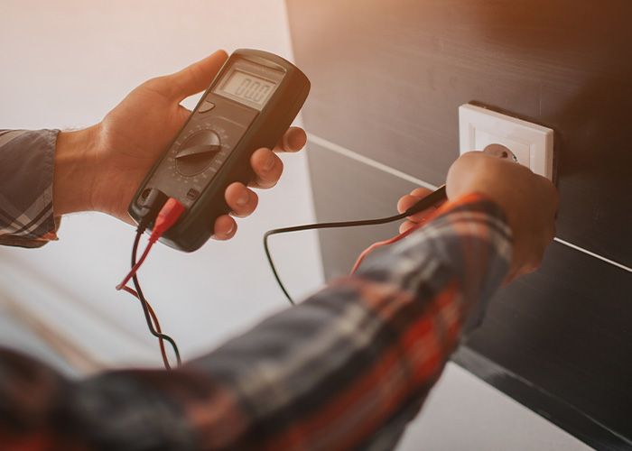 an electrician testing an outlet with a multimeter