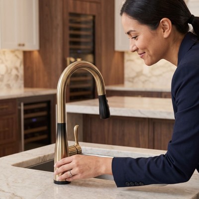 A close-up view of a person’s hands interacting with a sleek, modern matte black kitchen faucet.
