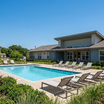 Lounge chairs sit beside a sparkling, sunlit swimming pool.