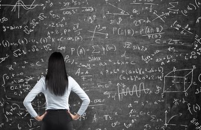 a woman in front of a black board filled with math equations