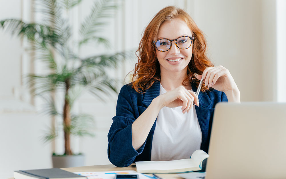 Smiling woman sitting at a desk with a laptop