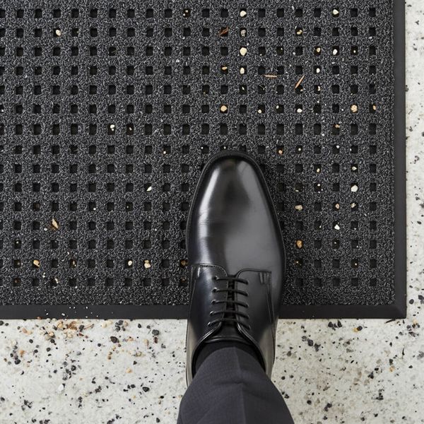 Close-up of a commercial walk-off mat placed over a polished granite floor to trap dirt and grit. foot.jpg