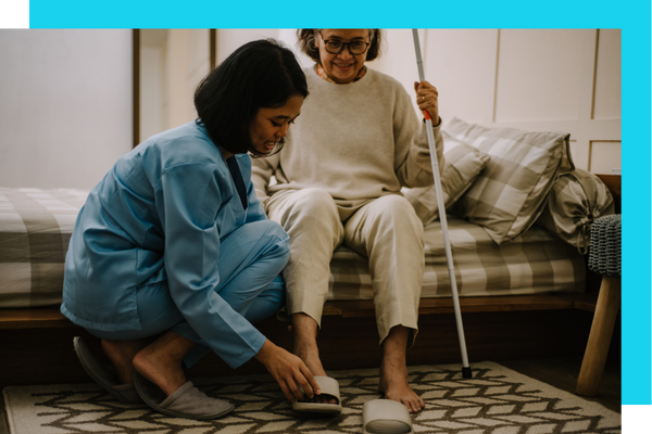 Caretaker placing slipper on patients foot