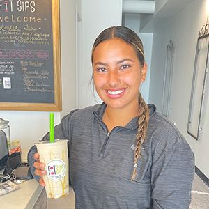 a fit woman holding a fit sips smoothie