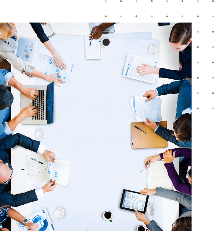 top down view of a meeting table surrounded by people and paperwork