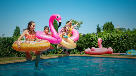 kids jumping into pool with floaties