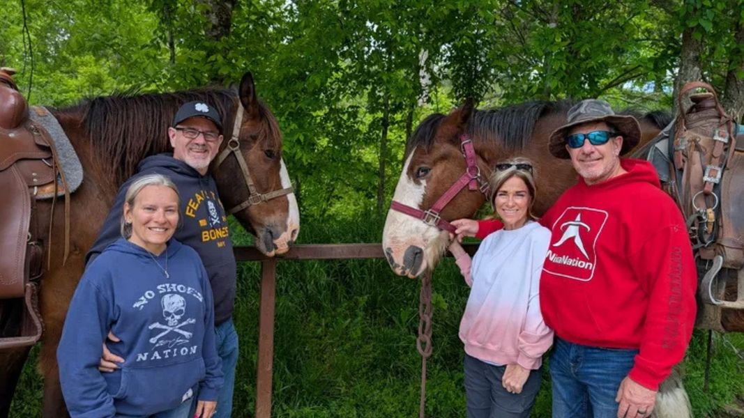 Two couples pose with Clydesdale horses