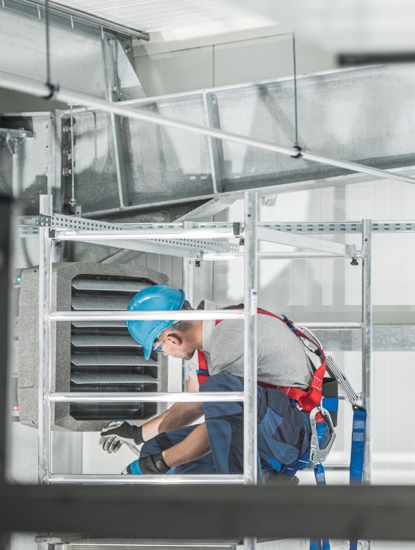 A commercial HVAC professional inspecting large ductwork
