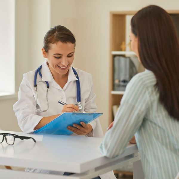 doctor talking to patient, writing on clipboard