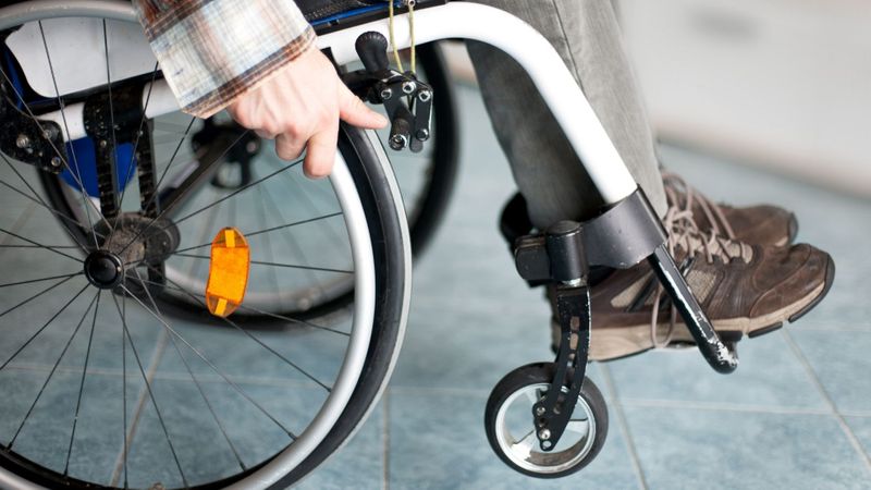 close up view of hands pushing wheel on wheelchair