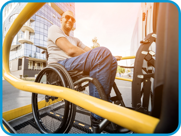 man in wheelchair getting onto / off of bus ramp, smiling. dramatic lighting / low shot