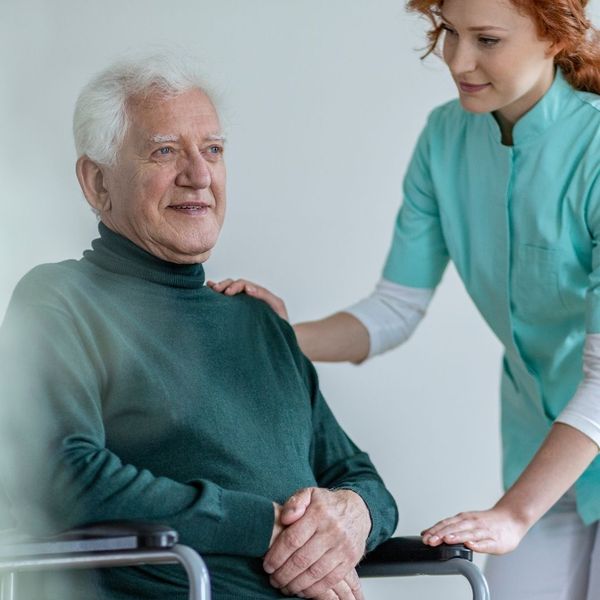woman assisting older man in a wheelchair