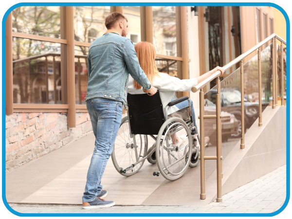 man pushing woman in wheelchair up a ramp
