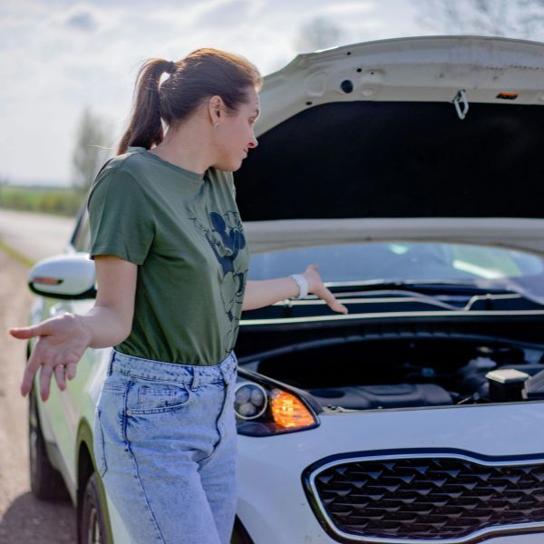woman looking under hood of her car woman looking under hood of her car