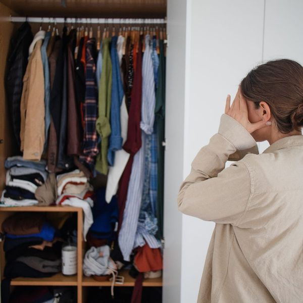 woman staring at closet overflowing with clothes