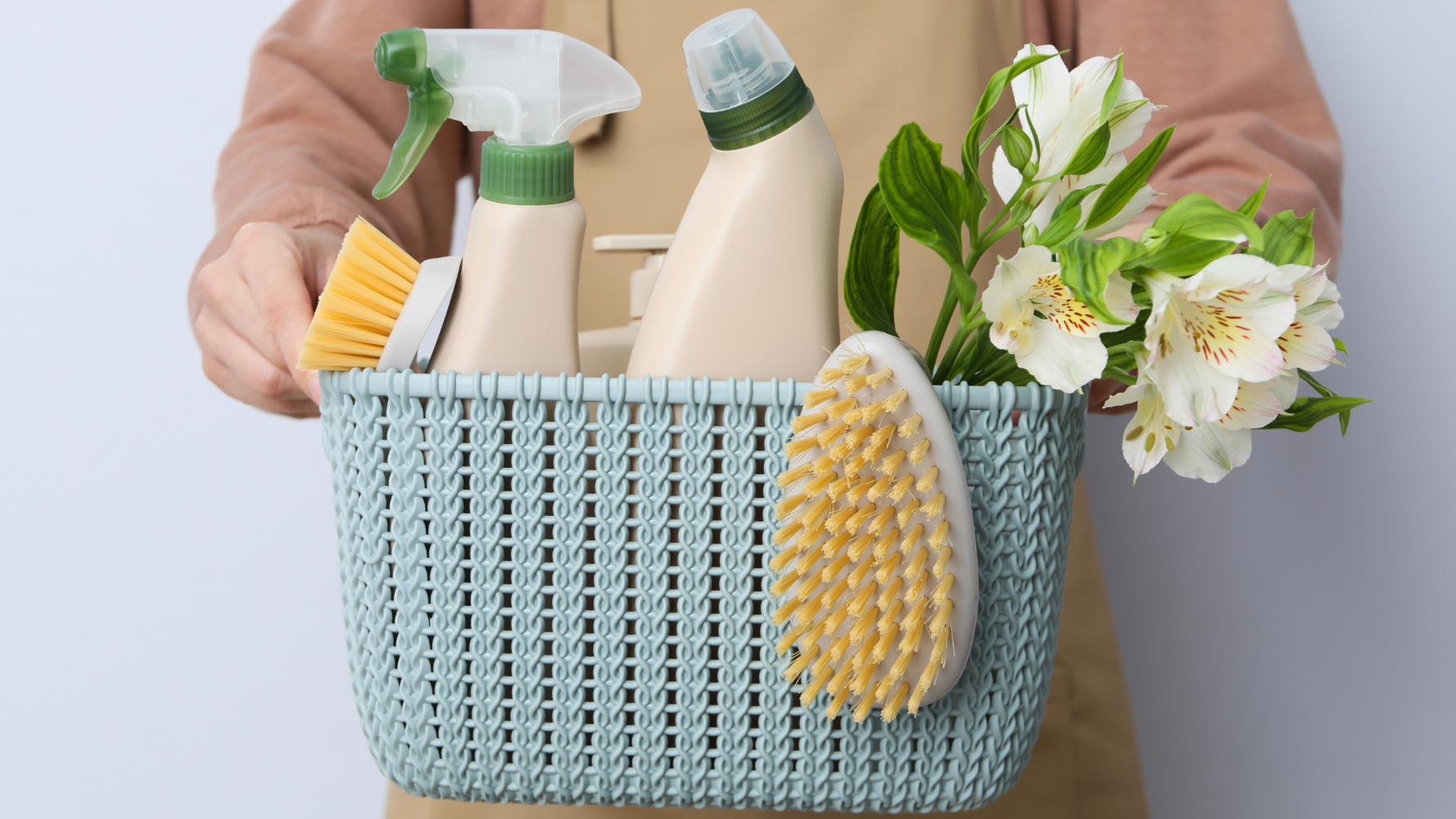 Person holding a bucket of green cleaning products. 