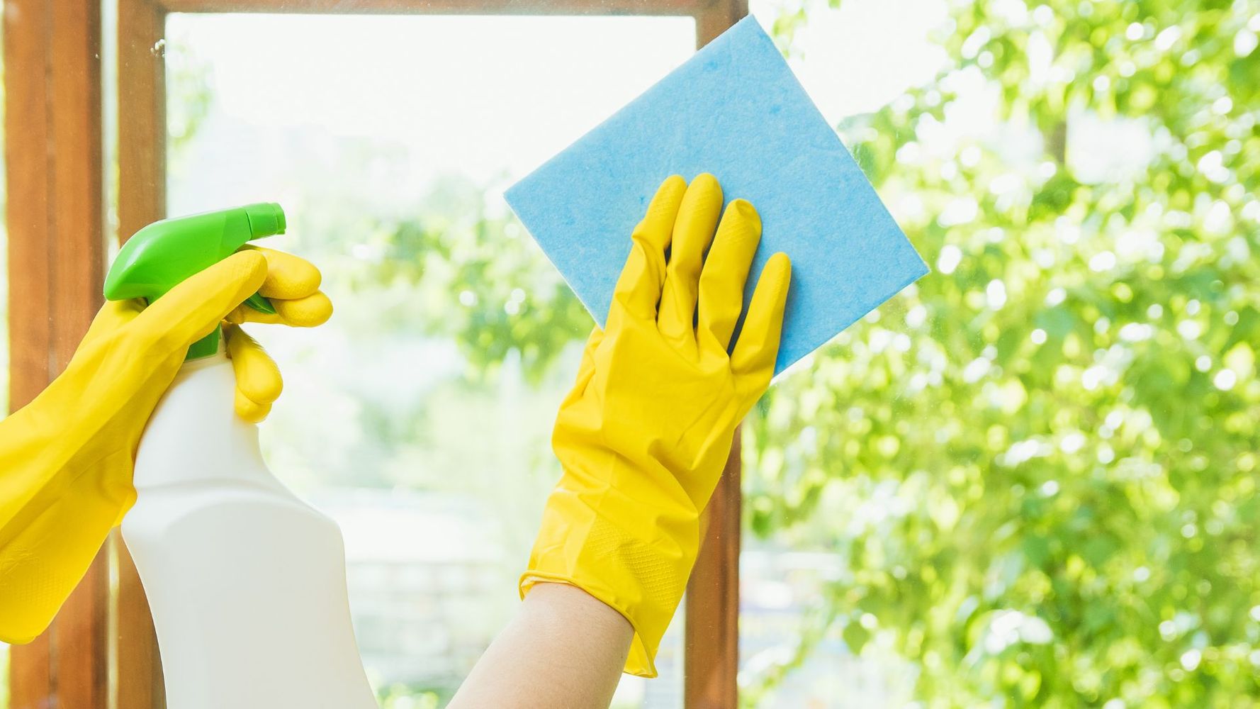 A person wearing yellow gloves cleaning a window 