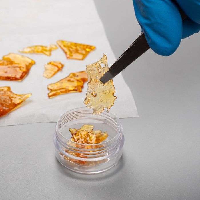 Dab wax being picked up out of a container with tweezers. 