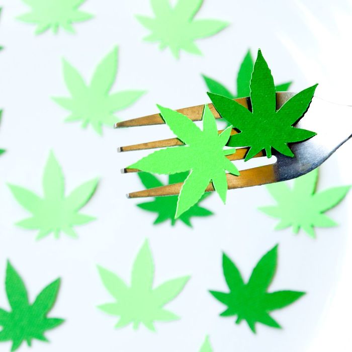 Fork picking up green pieces of paper shaped like weed leaves. 