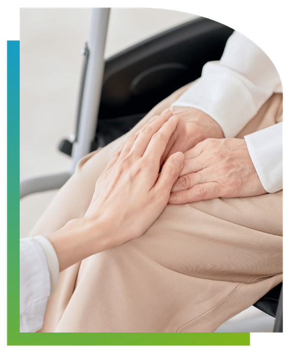 Close-up of a caregiver's hand gently resting on an elderly person's hands in a comforting gesture.