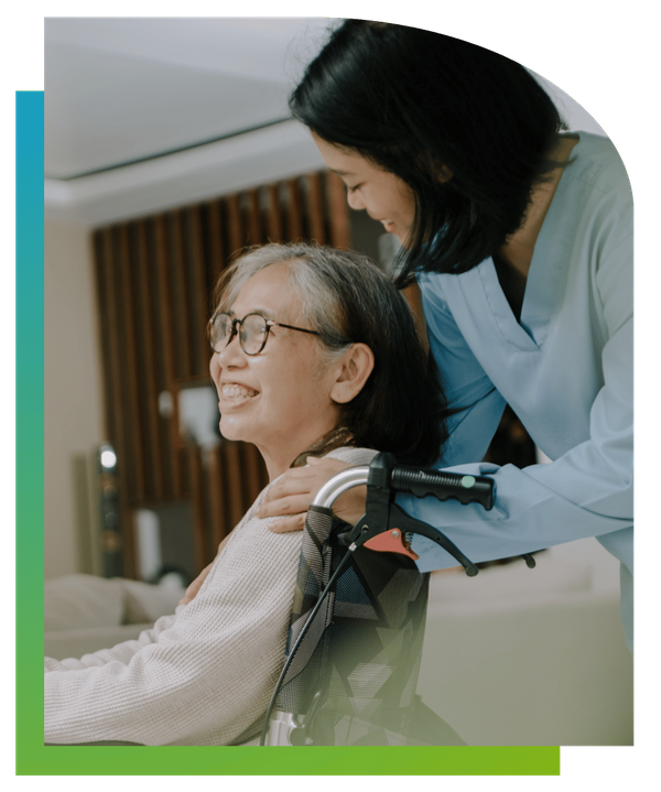 An elderly woman in a wheelchair sharing a joyful laugh with a female caregiver.