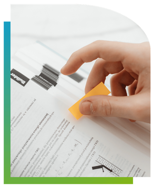 Close-up of hands organizing documents in a binder and using a yellow sticky tab.