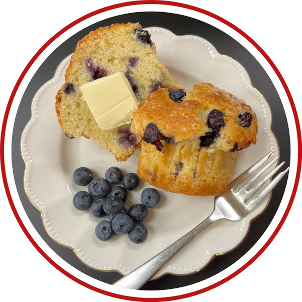 sliced blueberry muffin on plate with fork and fresh blueberries