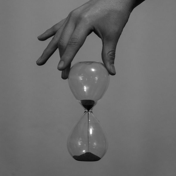 A person's hand holding an hourglass