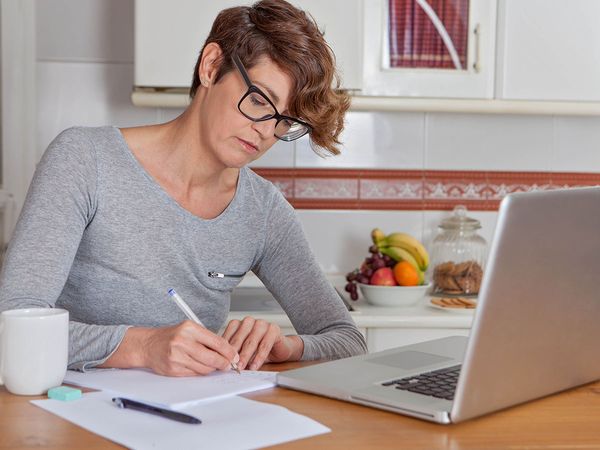 Woman with glasses and laptop working at home.