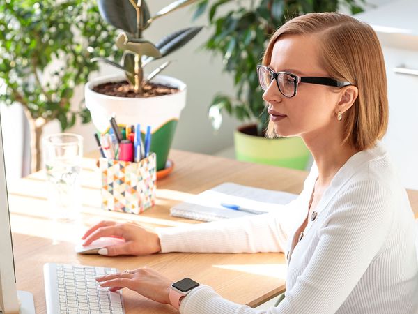 Freelancer woman in glasses working on a computer from her home office.