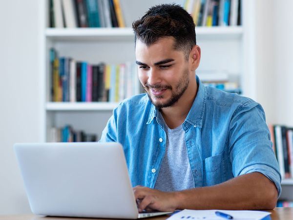 Man sending email with laptop at home.