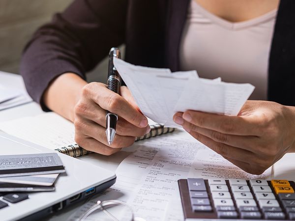 Young woman checking bills, taxes, bank account balance and calculating expenses.