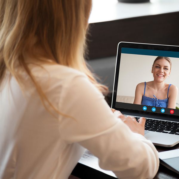 Two young women chatting online by making a video call on a laptop.