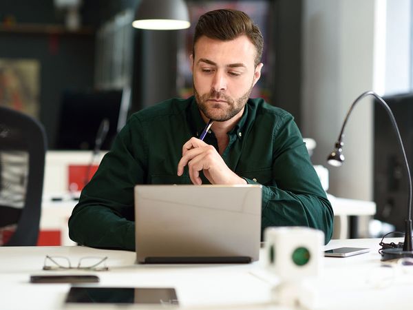 Young man studying with a laptop computer on white desk.