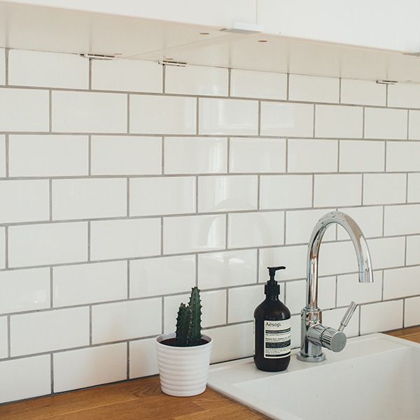 White tile backsplash by a laundry room sink