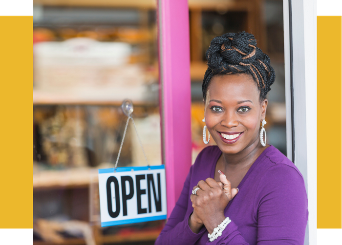 a woman smiling in front of the open sign of her business
