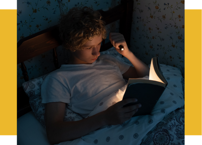 Man reading at night with flashlight.