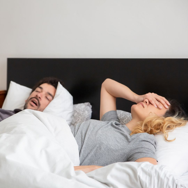A couple sleeping in bed, with one spouse snoring. A couple sleeping in bed, with one spouse snoring.