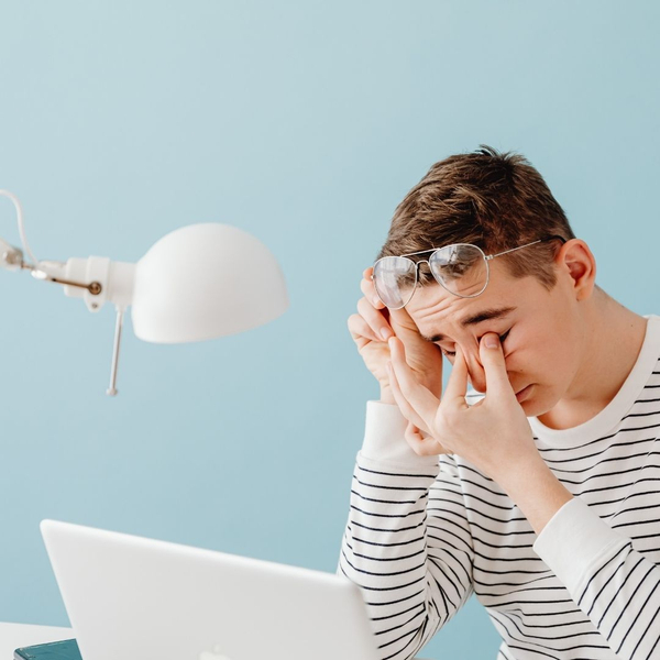 tired person at computer rubbing eyes 
