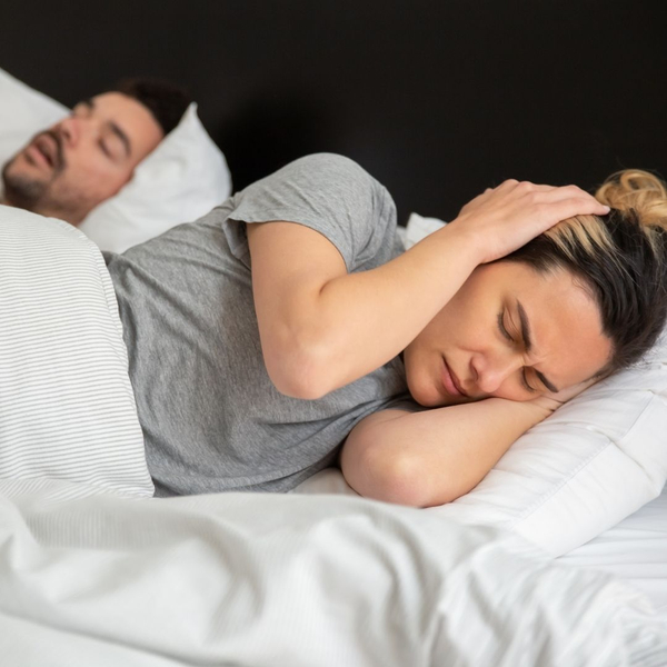 woman covering ears as man is snoring loudly woman covering ears as man is snoring loudly