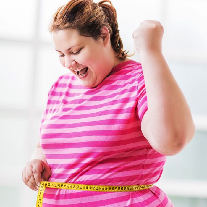 Woman happily measuring her waistline