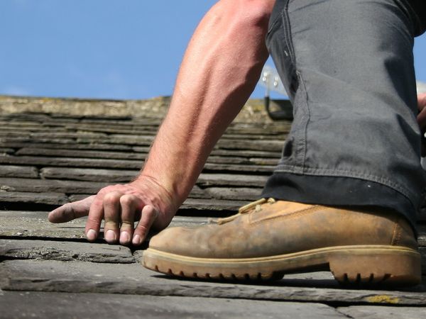 A roofer laying shingles on a roof.