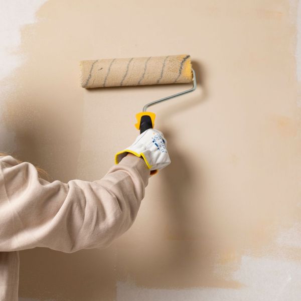 roller putting beige paint on a wall