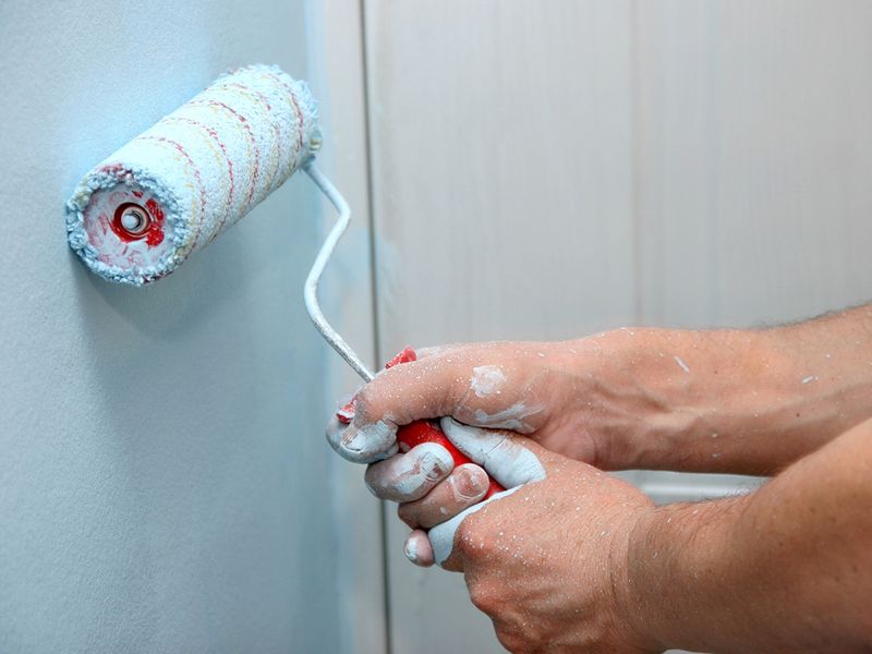  A paint roller adding blue paint to a wall.
