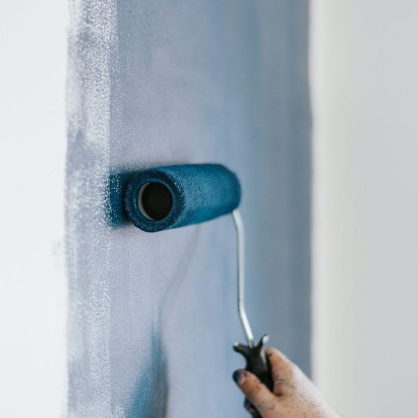 roller putting blue paint on a wall