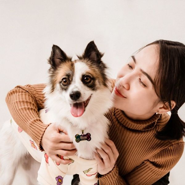A woman posing with her dog, who is wearing a sweater
