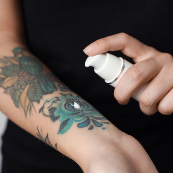 Woman applying aftercare lotion to tattoo