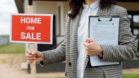 realtor holding home for sale sign 