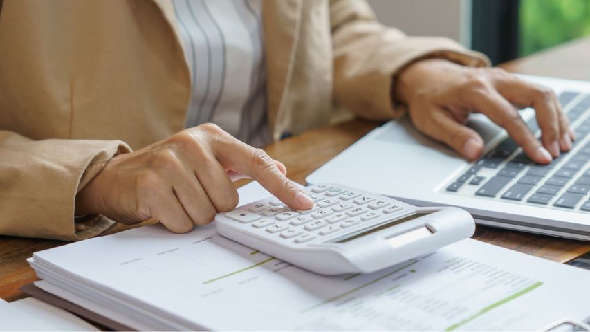 person using calculator and computer to budget